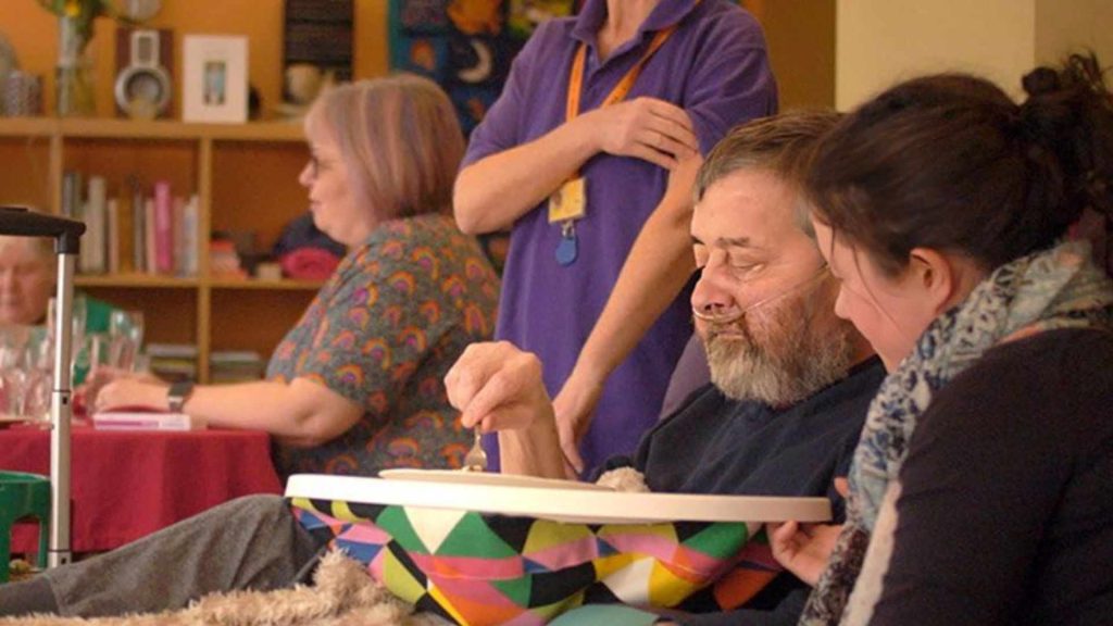 Volunteer helping patient eat.