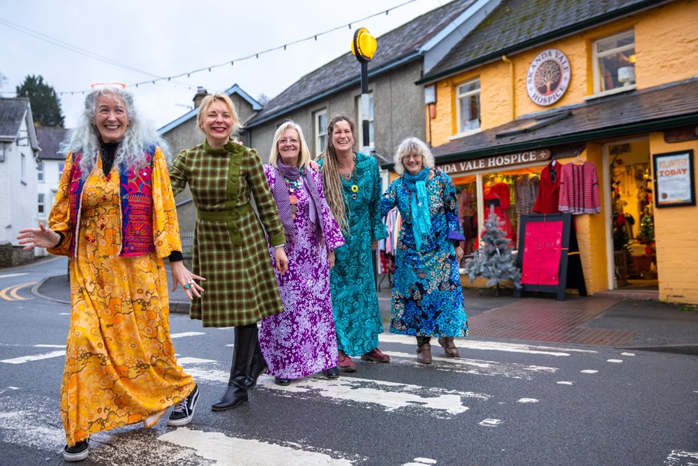 Our retail volunteer team in colourful clothes on the zebra crossing outside our charity shop in Newcastle Emlyn.
