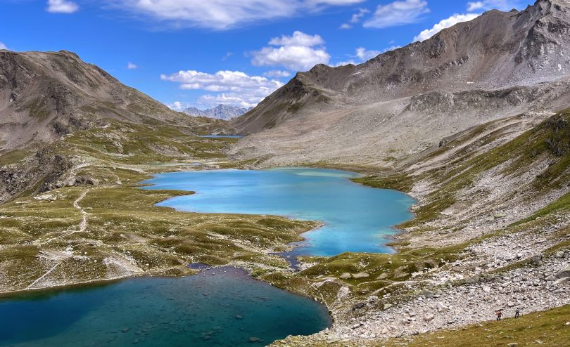 Hikers beside a turquoise glacial lake in the Swiss Alps.