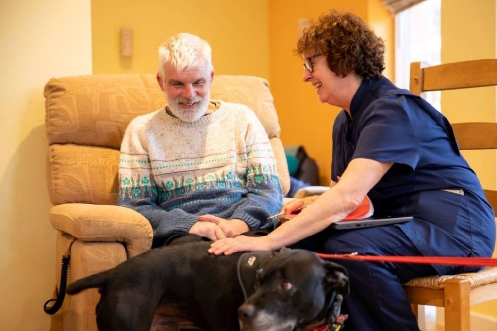 Volunteer and patient stroking a black dog.